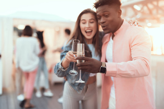 Portrait of smiling male and cheerful woman clanging alcohol beverage while embracing during party