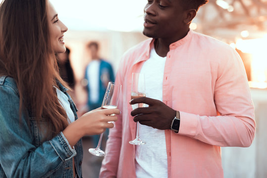 Outgoing woman talking with positive man while drinking glasses of champagne during party indoor