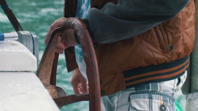 Hands hold steering wheel of the boat