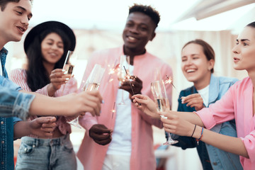 Satisfied man telling toast while having fun with cheerful comrades. They holding indian light and tasting alcohol liquid