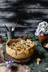 delicious pie with mushrooms and potted flowers on wooden table