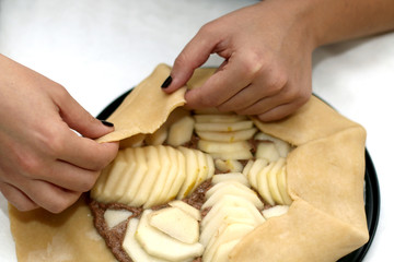 Unrecognizable person making a pear and almond galette. Selective focus.
