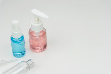 close up of the pink, blue and clear liquid containers with a plastic pipette on white background