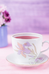 Obraz na płótnie Canvas Porcelain cup of raspberry tea on a pink background. Free space