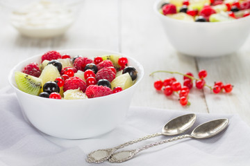 Fresh fruit salad(kiwi,grapefruit,raspberry, currant) for two on a natural wooden background. Light photo