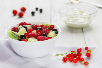 Fresh fruit salad. Yogurt. Natural wooden background