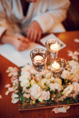 Composition of white flowers and candles on the table. Wedding decoration. Woman signing papers