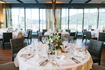 Elegant white round wedding banquet table with flowers decoration indoors in restaurant. Wedding decoration concept