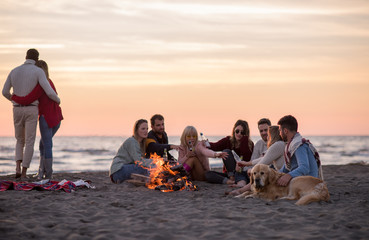 Fototapeta na wymiar Couple enjoying with friends at sunset on the beach