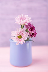 Pink and purple delicate chrysanthemums in vase on a light wooden background. Free space