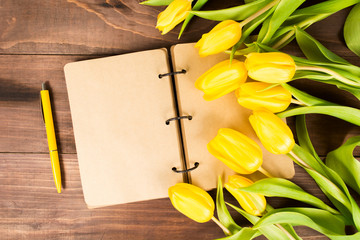 Open book with yellow tulips with pen for holiday