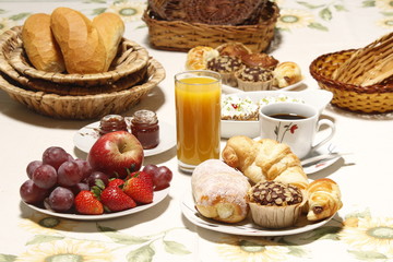 Obraz na płótnie Canvas Mesa de café da manhã, com maçãs, morango, suco de laranja, pães, croissant e café.