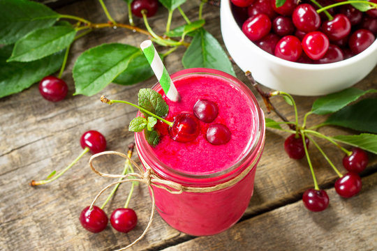 Cherry milkshake or smoothie on a dark wooden table. Healthy juicy vitamin drink diet or vegan food concept.