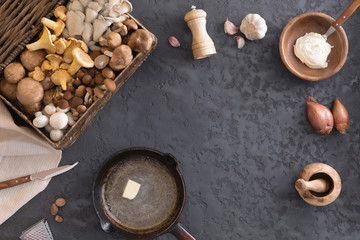 Top view of preparation and frying of edible wild mushrooms, food photo. Mix of chanterelle, portobello, shiitake in Cast-iron pan. Cooking with spices, butter, parsley, onion, leek, garlic.