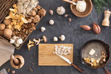 Top view of preparation and frying of edible wild mushrooms, food photo. Mix of chanterelle, portobello, shiitake in Cast-iron pan. Cooking with spices, butter, parsley, onion, leek, garlic.