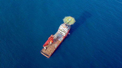 Aerial image of a Medium size red Offshore supply ship with a Helipad and a large crane