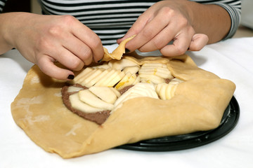 Unrecognizable person making a pear and almond galette. Selective focus.
