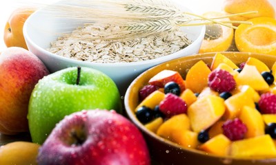 Raw oats in bowl and fruit salad, apples on the wooden table