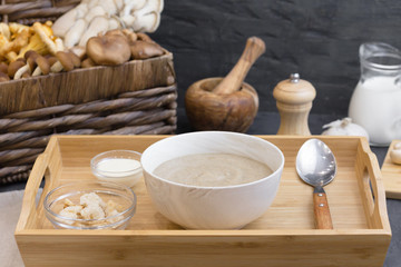 Mushroom cream soup with wild fungi, top view on dark textural background with fresh ingredients