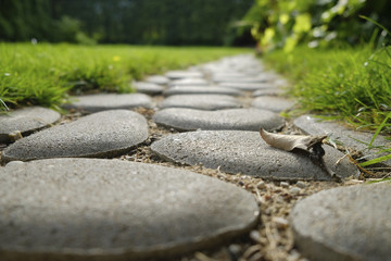 Close up. Path from cobble-stones in a grass in a garden