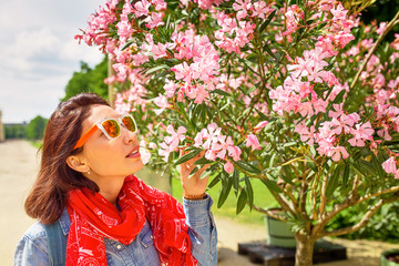Woman sniffing nerium oleander flowers in the garden