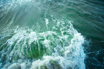 surface of turquoise ocean water with waves, spray and white foam