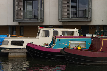Fototapeta na wymiar A photograph of three house boats or barges on canal in the United Kingdom docked next to residential flats