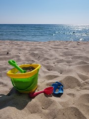 Fototapeta na wymiar children's toys on the beach with white sand on a sunny daychildren's toys on the beach with white sand on a sunny day