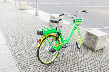 modern electric green bicycle parked at the sidewalk in the city
