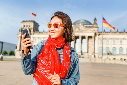 Beautiful young woman in casual wear communicating by her mobile internet phone at the Bundestag, Berlin