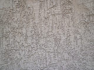 Texture of the gray plastered wall with small stones and ornamental chaotic scratches