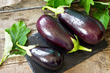 Fresh healthy raw Purple Eggplant on a kitchen wooden table. The concept of Diet menu. - obrazy, fototapety, plakaty