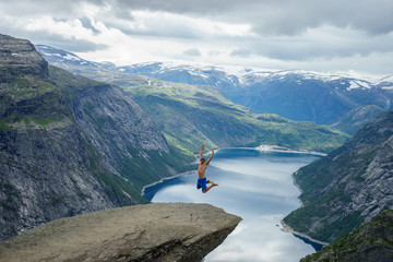 Young man jump on the edge Trolltunga. Norway