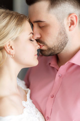 Happy wedding couple hugging and kissing. Beautiful young bride and groom, just married. Couple in love. Shallow focus and some noise.