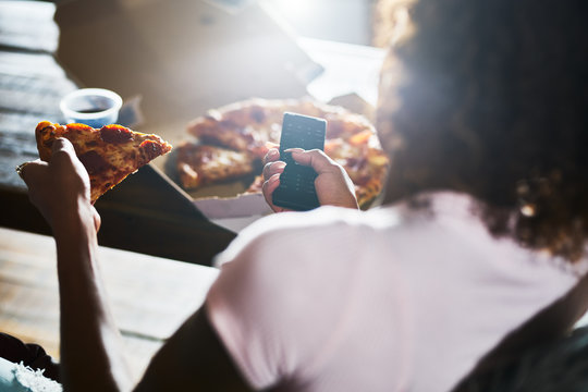 woman staying up late relaxing at home watching tv and eating pizza