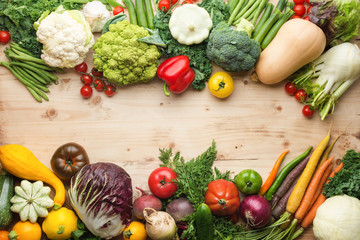 Fresh farm produce, organic vegetables and herbs on pine wooden table, healthy background, copy space for text in the middle, top view, selective focus