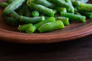 Raw green beans on a clay plate.