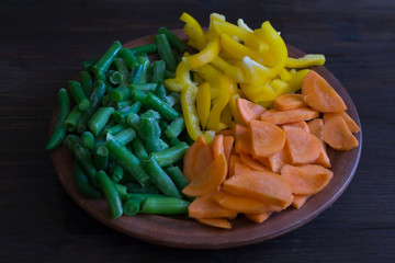 Raw vegetables on a clay plate for cooking.
