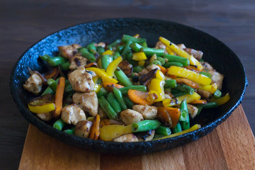 Stewed chicken with vegetables in a black pan.