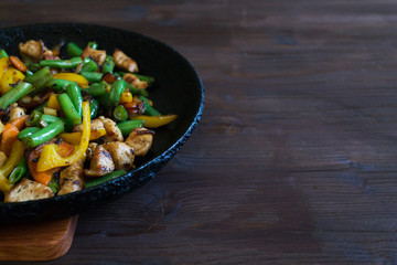 Stewed chicken with vegetables in a black pan.