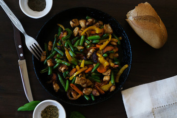 Stewed chicken with vegetables in a black pan.