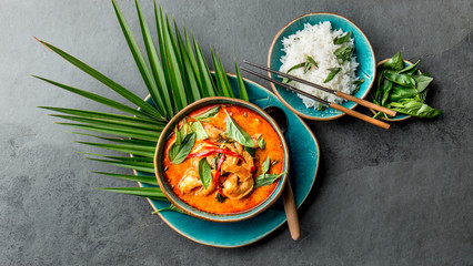 THAI SHRIMPS RED CURRY. Thailand Thai tradition red curry soup with shrimps prawns and coconut milk. Panaeng Curry in blue plate on gray background - obrazy, fototapety, plakaty