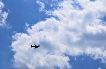 Blue sky and white clouds with silhouette of airplane flying, GA USA.
