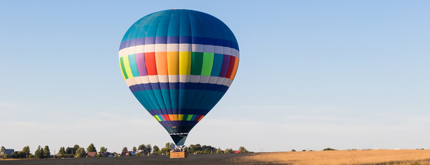 Colorful hot-air balloon flying over the forest and field, banner