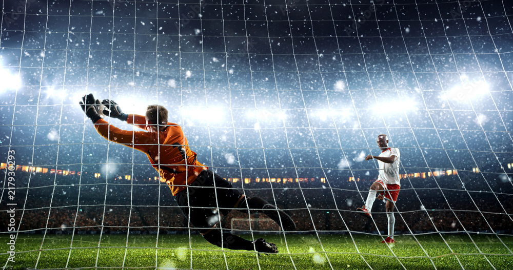 Wall mural Attacker scores a goal and celebrates victory on a professional soccer stadium while it`s snowing.