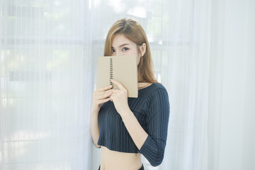 Close up of sexy beautiful Asian woman hold notebook and look to camera