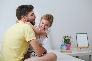 Father and daughter playing on bed