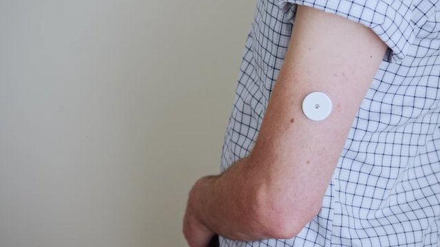 A man brings to the hand the reading device to the sensor for measuring glucose