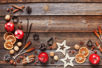 Christmas composition with red apples, walnuts, cinnamon and  other ingredients and accessories for the celebration of Christmas and New Year. Close-up, top view on rustic wooden background