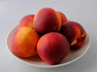 Still life of peaches. A few fresh peaches on a white plate.